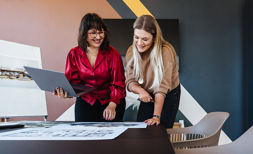 Two women discussing designs in a modern workspace