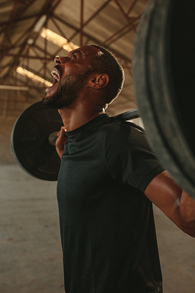 Strong man doing intense barbell workout