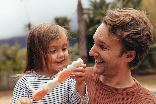 Little girl with her father outdoors holding a candy