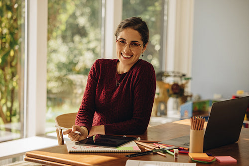 Smiling female designer sitting at home