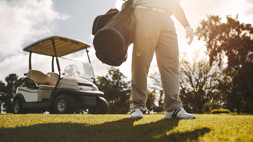 Golfer standing on the golf court with his bag