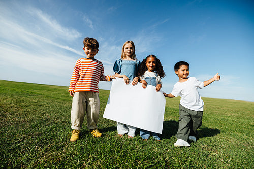 Children hold a blank sign in open field