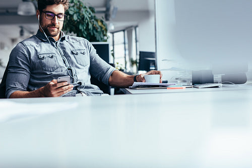 Young businessman using smart phone in office
