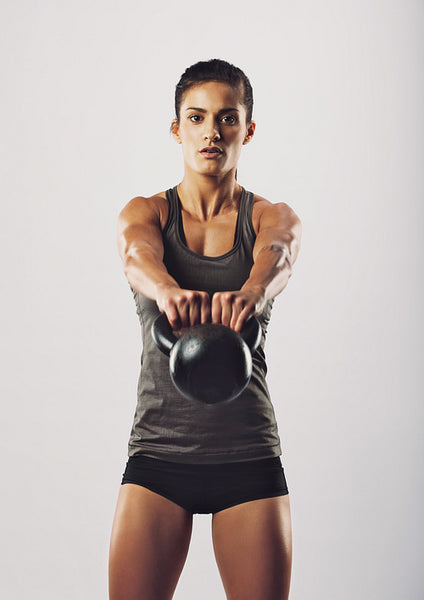 Young fit woman performing kettlebell swing exercise