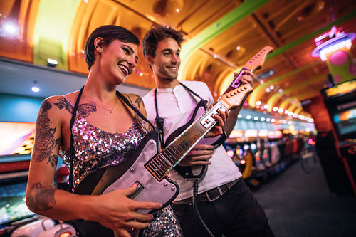 Couple playing guitar arcade game looking at the console