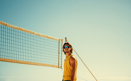 Smiling male athlete playing beach volleyball in summer games