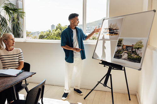 Male architect presenting designs to a female colleague in a modern office