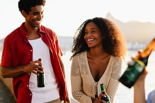 Joyful friends celebrating outdoors with drinks at sunset in Brazil
