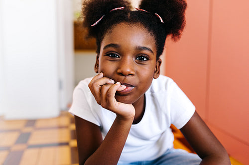 Confident young girl with afro hair sitting at home