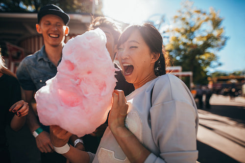 Young friends eating cotton candy outdoors