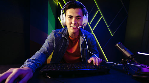 Young man live streaming a first-person shooter video game on a gaming computer