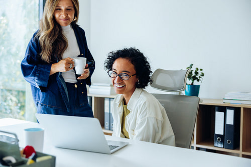 Female manager supporting employee work at laptop in modern office