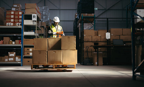 Logistics worker reading a clipboard in a warehouse