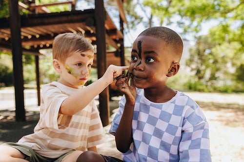 Two young friends painting each other during a playful outdoor activity