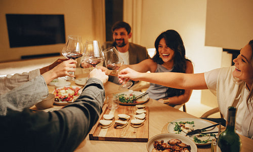 Friends enjoying a lively dinner with food and drinks around the table