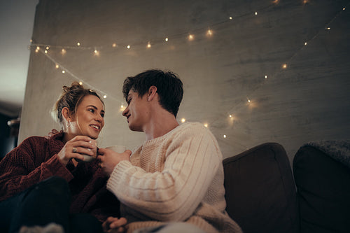 Cozy couple sitting on sofa and having coffee
