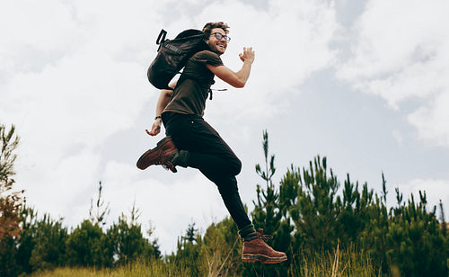 Happy man jumping during his walk in the forest