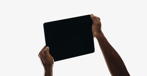 Hands holding a black tablet on a white background