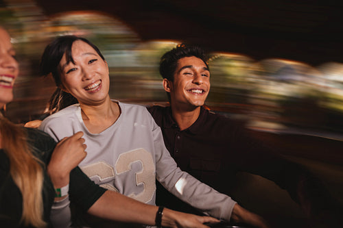 Three young people on amusement park ride.
