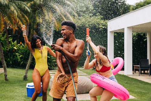 Friends enjoy water hose party in tropical backyard