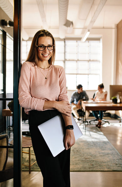 Smiling young woman leaning to office doorway
