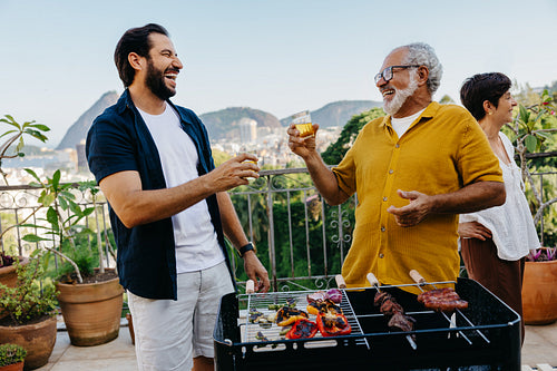 Family enjoying a Brazilian churrasco with laughter and grilled food outdoors