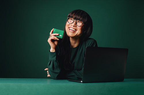 The woman reviews online payment details with a laptop and credit card