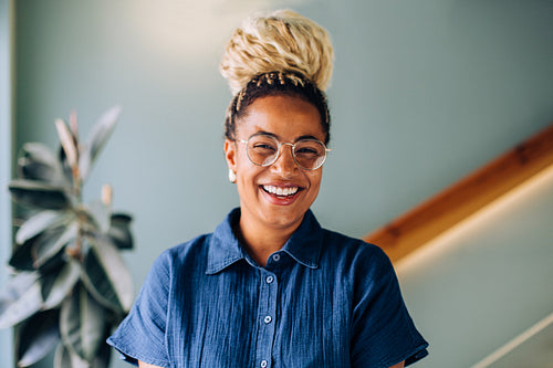 Smiling woman in glasses and braided hairstyle posing indoors