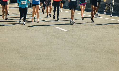 Marathon runners on tarmac road during a sunny day