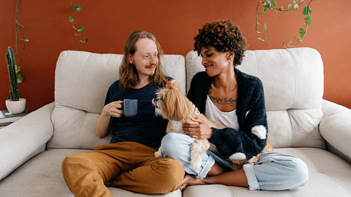 Couple relaxing on the couch with their cute dog at home