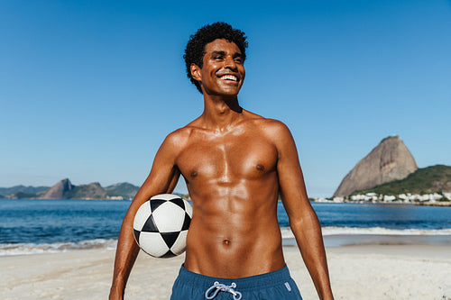 Athletic man with soccer ball enjoying Praia do Flamengo under a bright blue sky