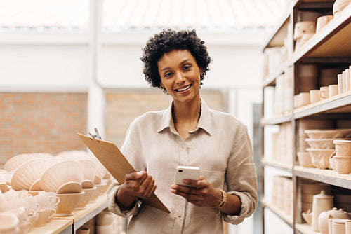 Happy female entrepreneur smiling at the camera in her ceramic shop