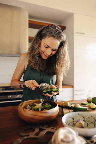 Happy vegetarian woman preparing a delicious buddha bowl at home
