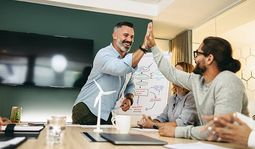 Successful businessmen high fiving each other during a meeting