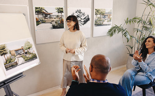 Team presenting architectural project receiving applause during a meeting in office
