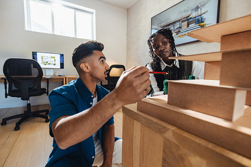 Architects discussing house model ideas at work in a modern office setting