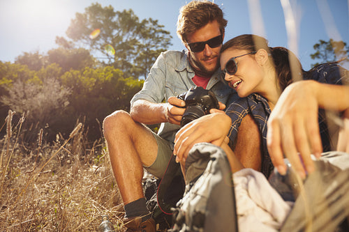 Couple on hiking trip taking a break sitting and looking at pictures