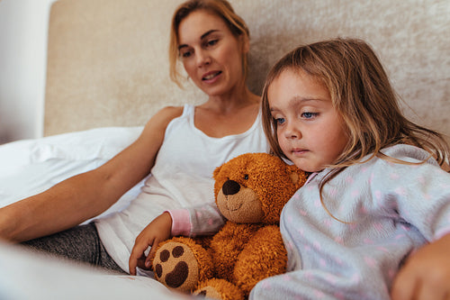 Mother and daughter reading a book in bed