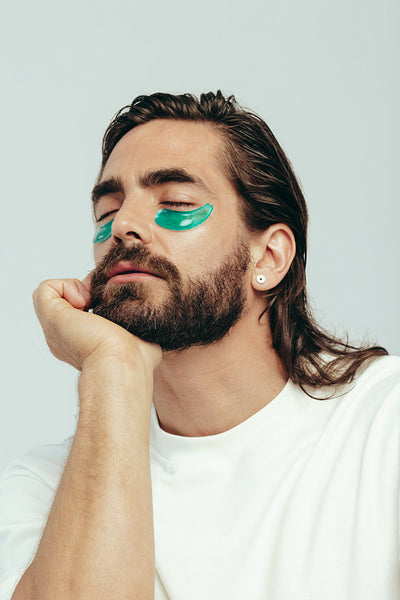 Man practicing skincare with under eye gel patches