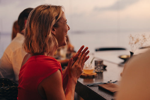 Woman clapping joyfully during a fine dining evening at a restaurant
