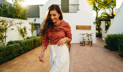 Smiling young tourist woman walking alone outdoors