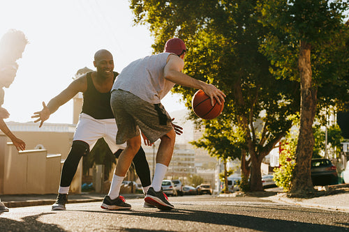 Men playing basketball on street