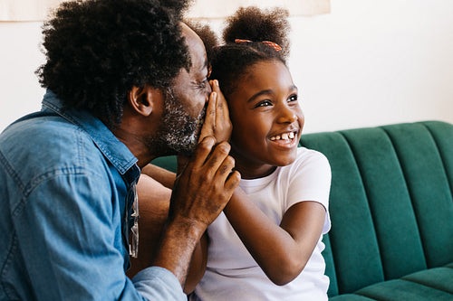Dad whispering to his daughter, creating genuine moments of joy at home