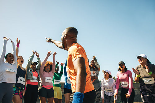 Excited runners gather at marathon starting line on sunny day