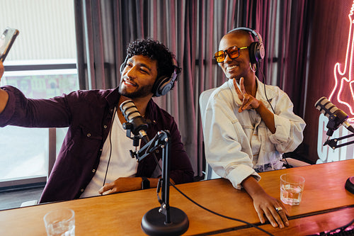 Podcast hosts enjoying a studio session taking a selfie while recording