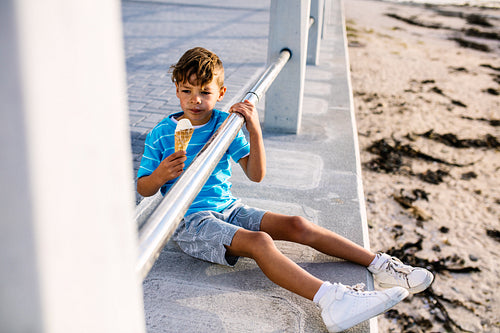 Boy eating an ice cream sitting near seashore