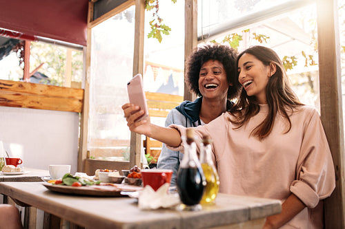 Couple having fun using smartphone at coffee shop