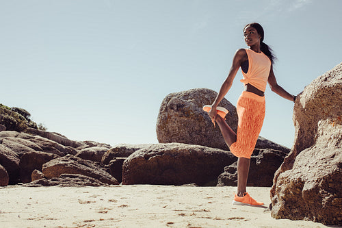 African woman doing stretching workout on beach