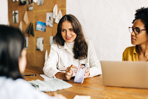 Fashion designers showing a clothing design to a client during a meeting