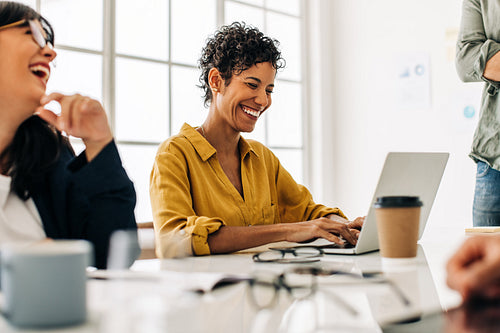 Business woman using a laptop in a meeting with her team
